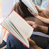 two people sitting next to each other reading books