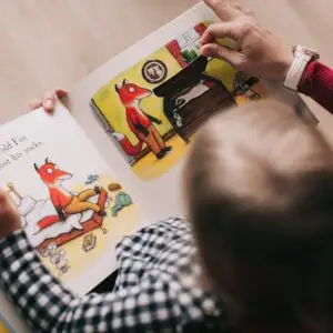 a toddler is in an adults lap reading a book