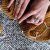 image of a person's hands knitting with brown yarn