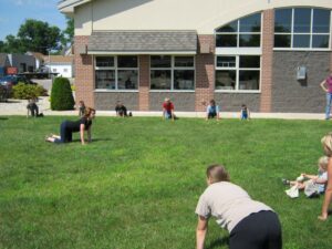 adults and children doing yoga on library lawn