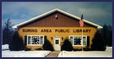 Original Suring Area Public Library building with two windows, one door, yellow and brown front