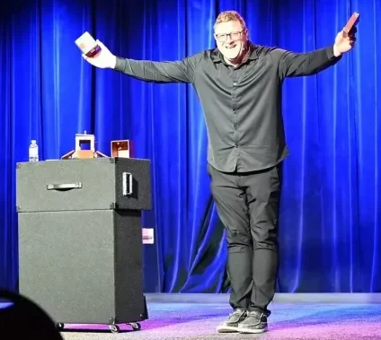 a magician is on stage with a trunk of tricks