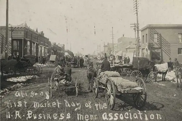 old black and white image of horse-drawn wagons and carts on a dirt road