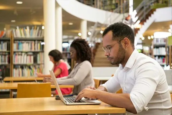 people doing research in a library with laptops